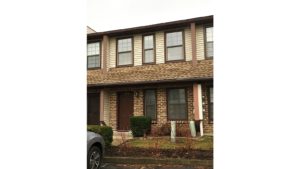 Exterior of townhouse with brick first floor, and yellow siding on the second floor