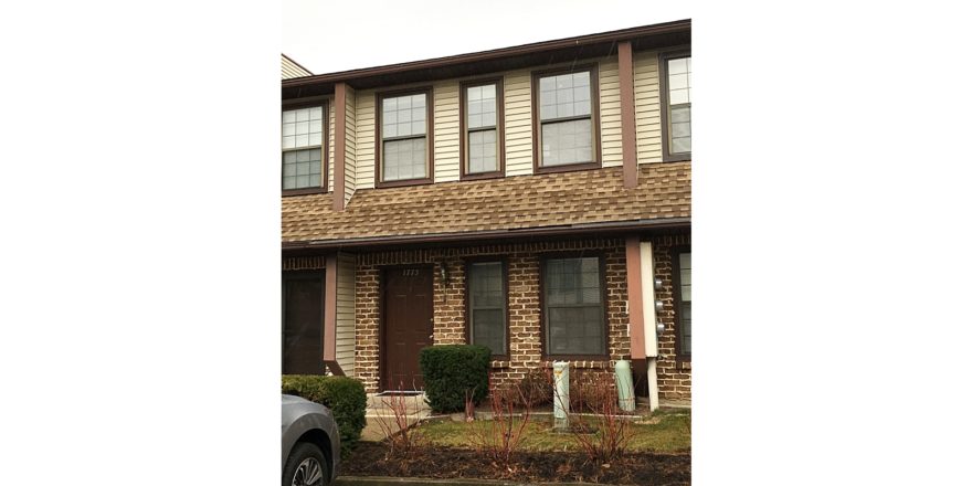 Exterior of townhouse with brick first floor, and yellow siding on the second floor