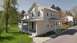 Exterior of house with yellow siding and, covered entry, and covered side porch