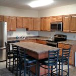 Open concept kitchen with wood-tone cabinets, island with barstool seating and stainless steel appliances