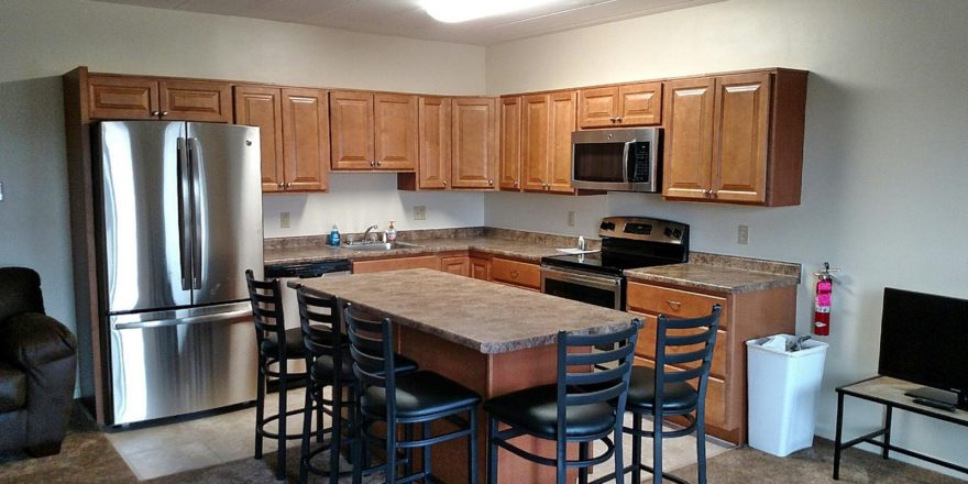 Open concept kitchen with wood-tone cabinets, island with barstool seating and stainless steel appliances