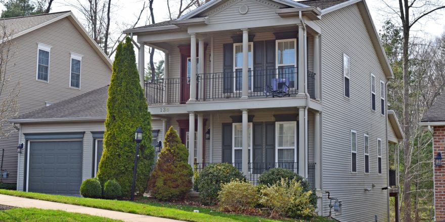 Exterior of two story house with large covered front porch, large balcony off the master bedroom, and large two car garage.