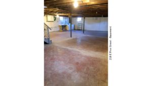 Unfinished basement with large wash tub, and side-by-side washer and dryer