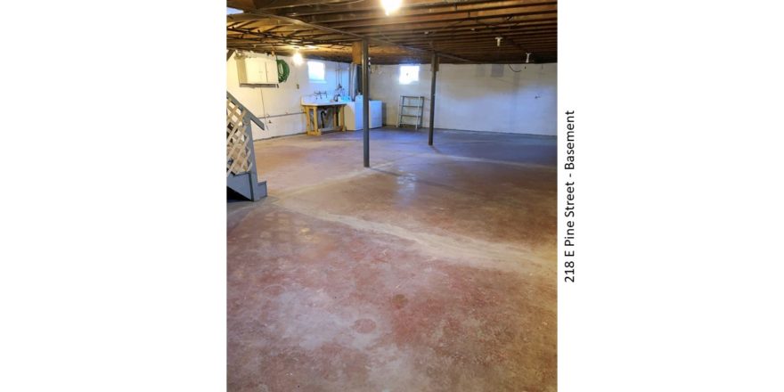 Unfinished basement with large wash tub, and side-by-side washer and dryer