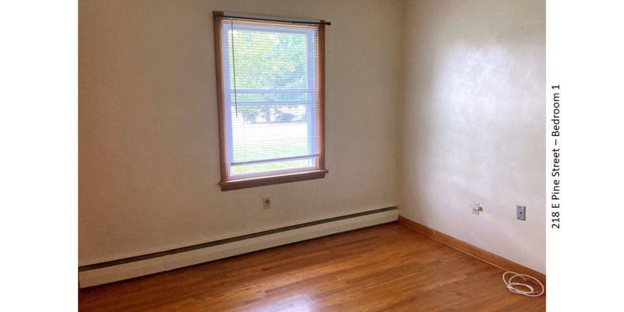 Unfurnished bedroom with hardwood floors and window