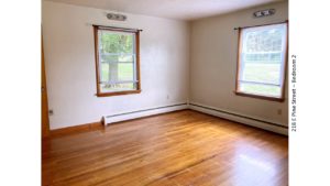 Unfurnished bedroom with hardwood floors and windows