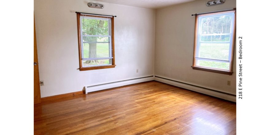Unfurnished bedroom with hardwood floors and windows