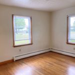 Unfurnished bedroom with hardwood floors and windows