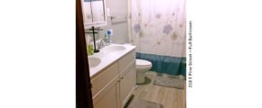 Bathroom with double sink vanity, medicine cabinet with mirror, toilet, and tub/shower combo with curtain