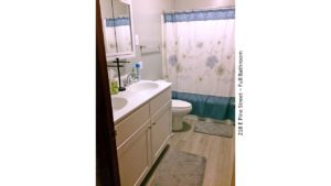 Bathroom with double sink vanity, medicine cabinet with mirror, toilet, and tub/shower combo with curtain