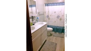 Bathroom with double sink vanity, medicine cabinet with mirror, toilet, and tub/shower combo with curtain