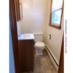 Half-bathroom with toilet, vanity, medicine cabinet with mirror, and window