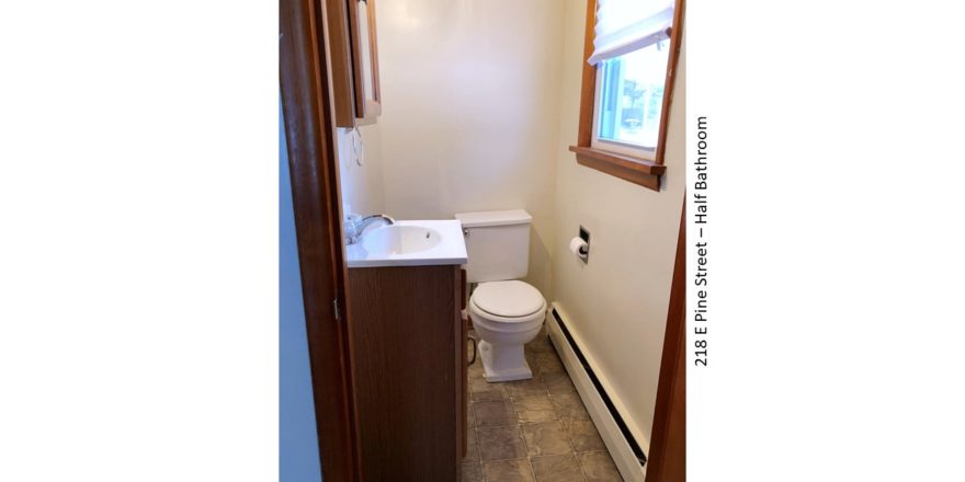Half-bathroom with toilet, vanity, medicine cabinet with mirror, and window