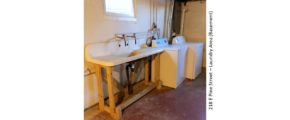 Unfinished basement with large wash tub, and side-by-side washer and dryer