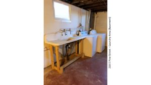 Unfinished basement with large wash tub, and side-by-side washer and dryer