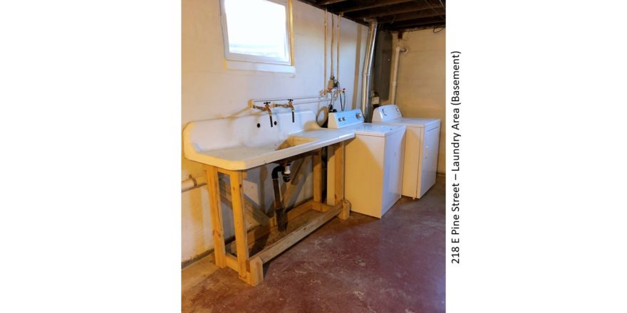 Unfinished basement with large wash tub, and side-by-side washer and dryer