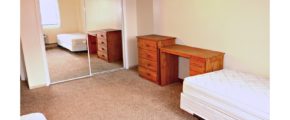 Bedroom with two twin beds, wooden desk, and wooden chest of drawers