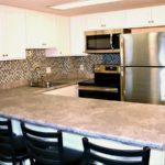 Kitchen with white cabinets, stainless steel appliances, sink, and barstool seating