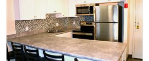 Kitchen with white cabinets, stainless steel appliances, sink, and barstool seating