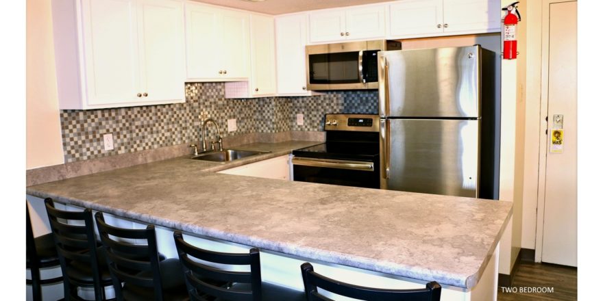 Kitchen with white cabinets, stainless steel appliances, sink, and barstool seating