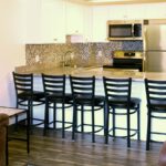 Kitchen with white cabinets, stainless steel appliances, sink, and barstool seating
