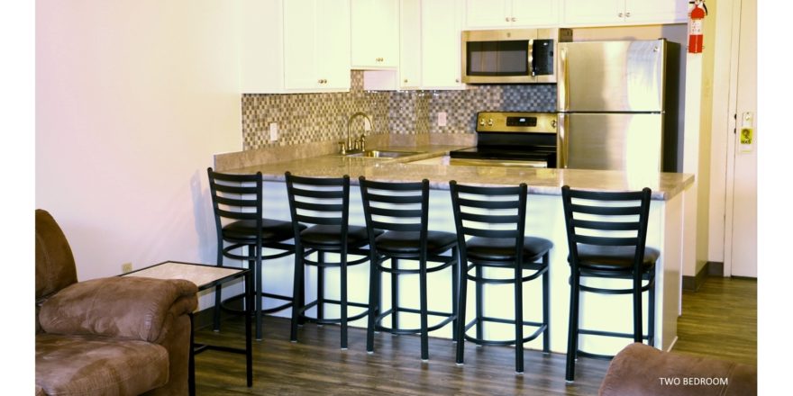 Kitchen with white cabinets, stainless steel appliances, sink, and barstool seating