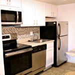 Kitchen with white cabinets, stainless steel appliances, barstool seating, and backsplash