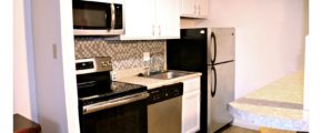 Kitchen with white cabinets, stainless steel appliances, barstool seating, and backsplash