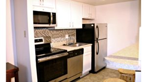 Kitchen with white cabinets, stainless steel appliances, barstool seating, and backsplash