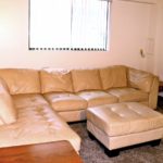 Living room with large sectional sofa, ottoman, accent tables, and TV stand