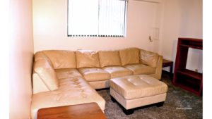Living room with large sectional sofa, ottoman, accent tables, and TV stand