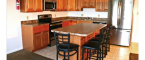 Kitchen with wood-tone cabinets, island with barstool seating, and stainless steel appliances