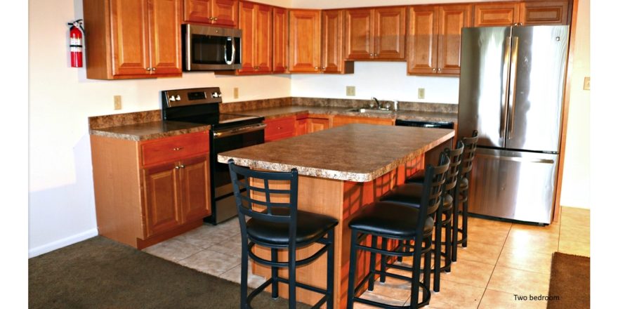 Kitchen with wood-tone cabinets, island with barstool seating, and stainless steel appliances