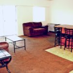 Open concept living room/kitchen with island with barstool seating, couches, and accent table