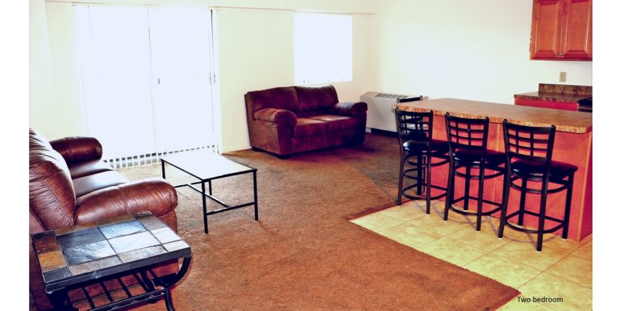 Open concept living room/kitchen with island with barstool seating, couches, and accent table