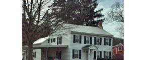 Exterior of two story house with carport. It has white siding, black shutters and a covered entry