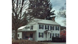 Exterior of two story house with carport. It has white siding, black shutters and a covered entry