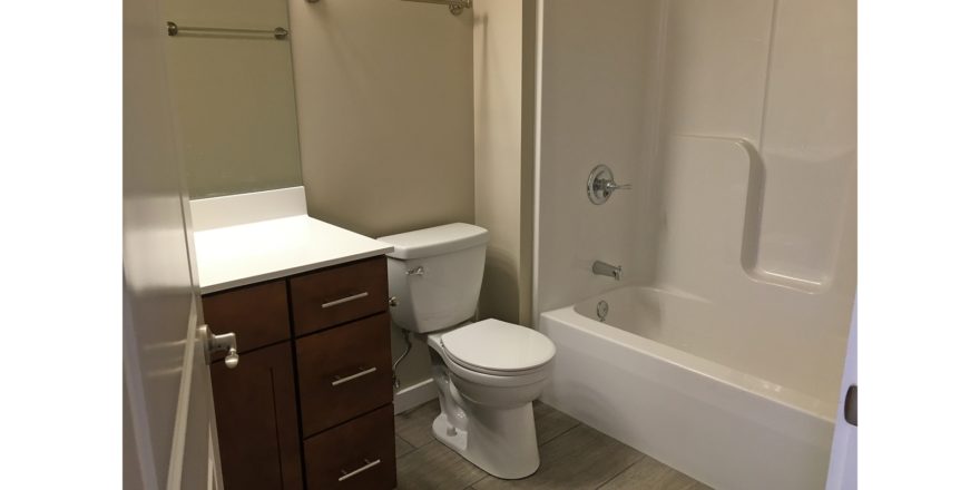 Bathroom with shower/tub combo, toilet, and vanity and mirror
