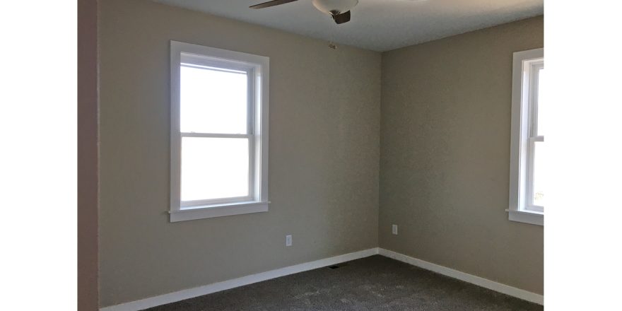 Carpeted, unfurnished bedroom with two windows
