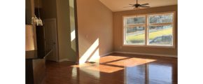 Living room with vaulted ceilings, hardwood floors, large picture window, and ceiling fan