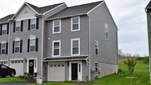 Exterior of townhouse with gray siding, black front door, with a one car garage and driveway