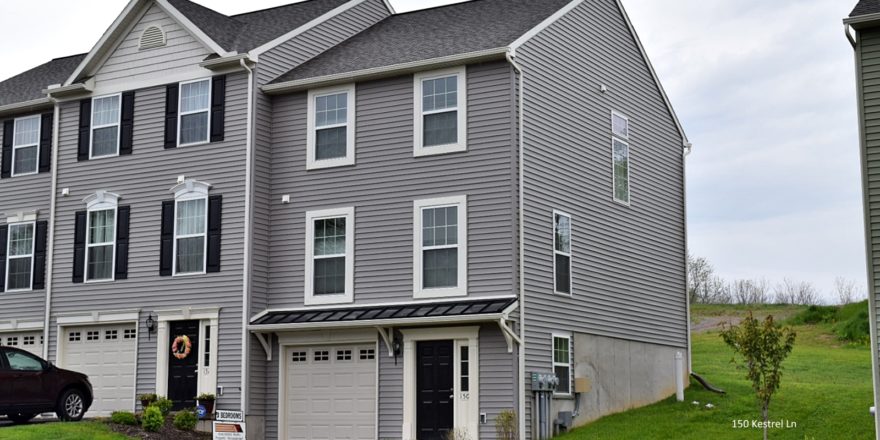 Exterior of townhouse with gray siding, black front door, with a one car garage and driveway