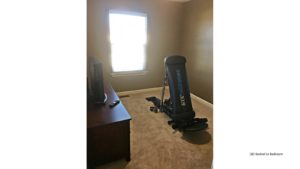 Carpeted bedroom with window, tv, tv stand exercise equipment