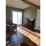Living room with wood-style flooring, leather armchair, credenza with pictures and sliding glass door