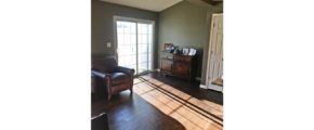 Living room with wood-style flooring, leather armchair, credenza with pictures and sliding glass door