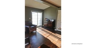 Living room with wood-style flooring, leather armchair, credenza with pictures and sliding glass door