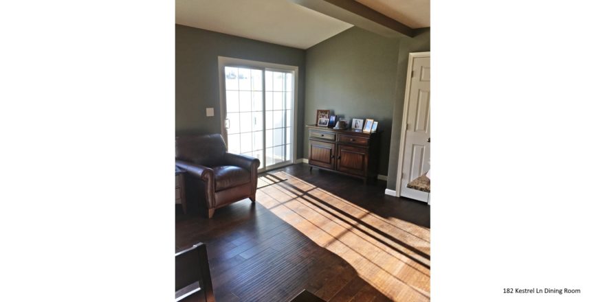 Living room with wood-style flooring, leather armchair, credenza with pictures and sliding glass door