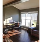 Living room with wood-style flooring, leather armchair, desk with computer and large window