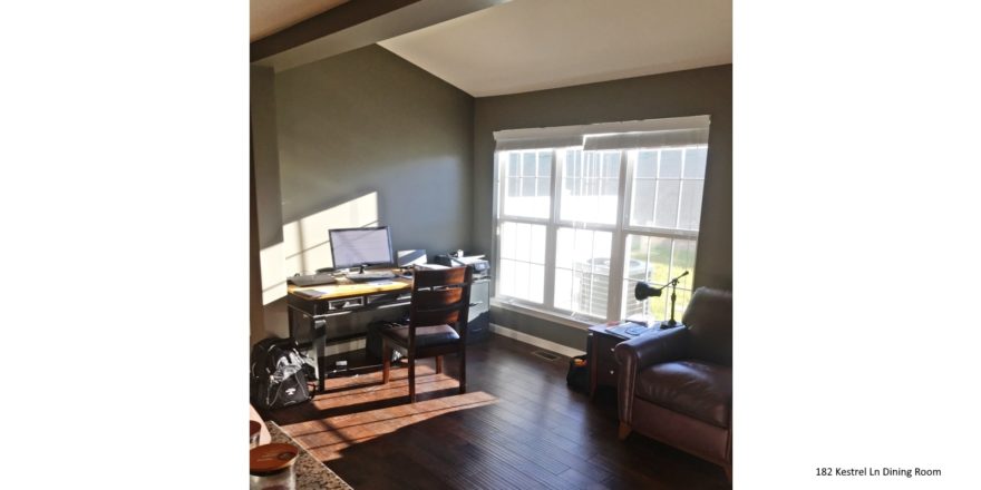 Living room with wood-style flooring, leather armchair, desk with computer and large window