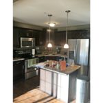 Kitchen with wood-style floor, stainless steel appliances, dark wood cabinets, and island